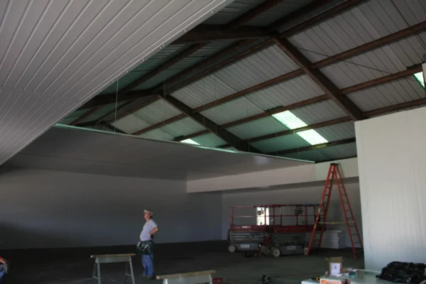 Workers installing insulated ceiling panels inside building